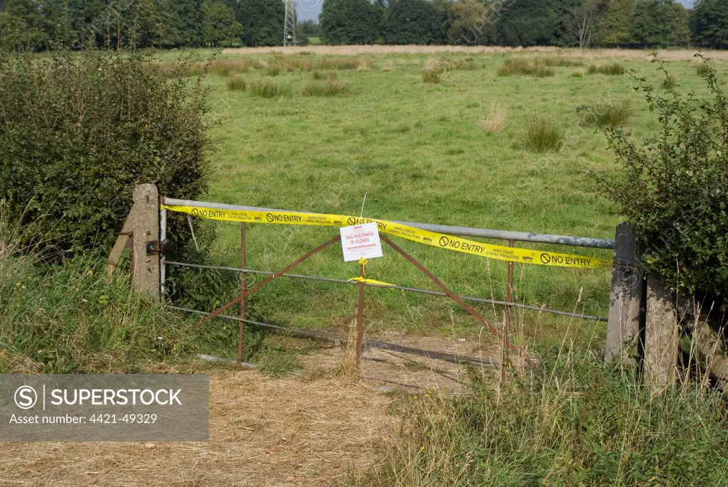 'This Footpath is Closed on Account of Foot and Mouth Disease' sign and 'No Entry, Animal Disease Control Precautions' tape on gate in farmland, Surrey, England, September 2007