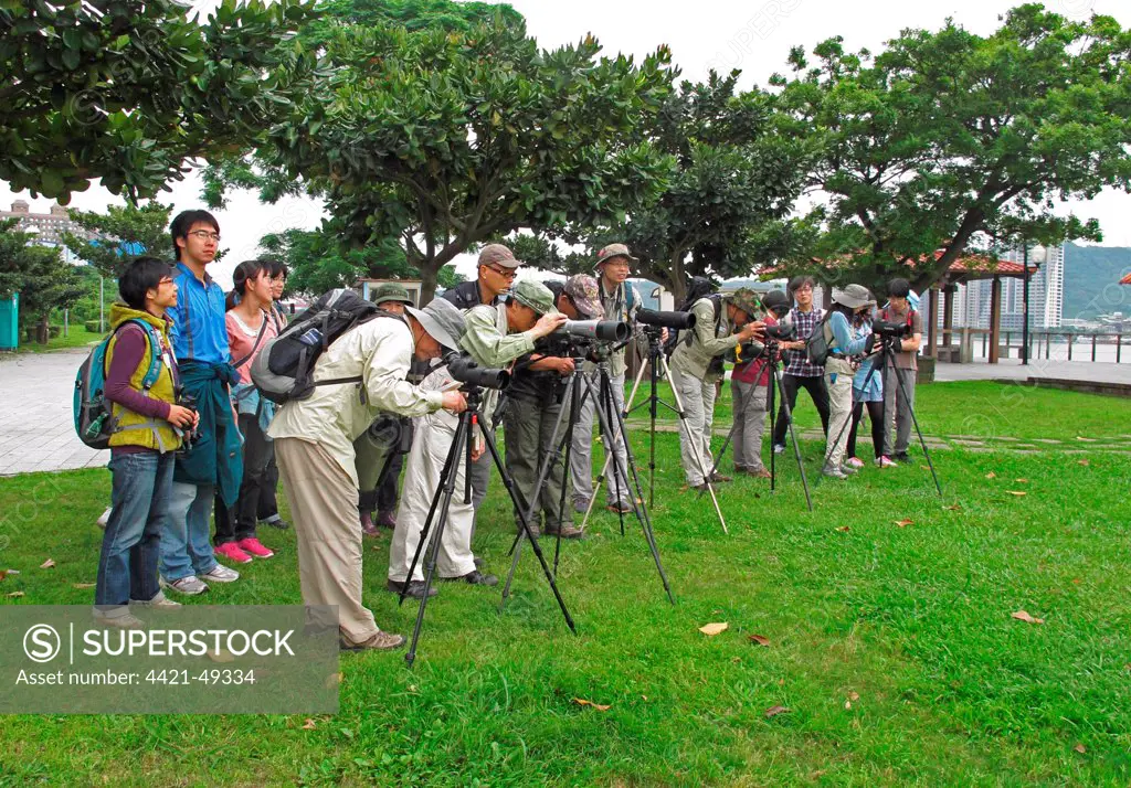 Taiwanese birdwatchers scanning estuary with telescopes, members of 'The Wild Bird Society of Taipei' on group outing, Taipei, Taiwan, April