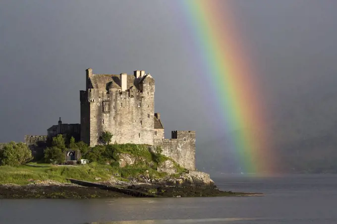 View of restored castle on tidal island in sea loch with rainbow, in evening sunlight, Eilean Donan Castle, Loch Duich, Ross and Cromarty, Highlands, Scotland, July
