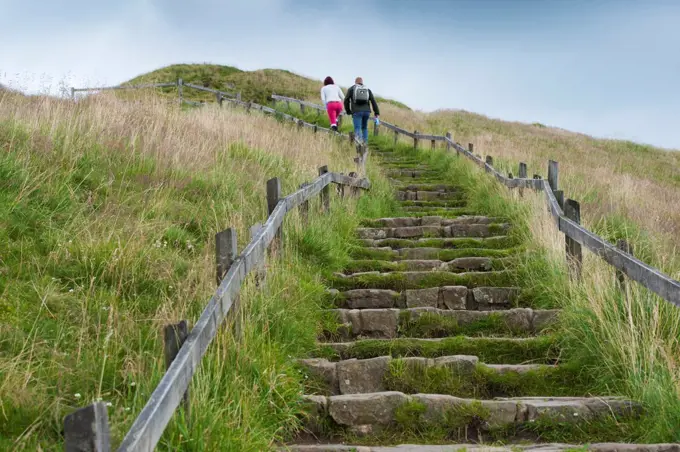 Walkers walking up steps, on limestone path to protect against soil erosion, Mam Tor, High Peak District, Derbyshire, England, august