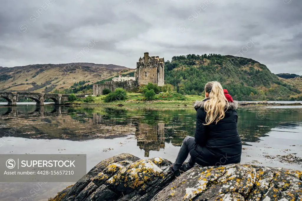 Woman enjoying view of remote, waterfront castle, Scotland