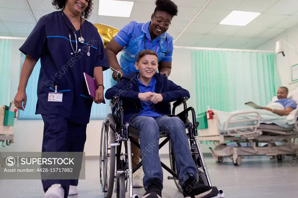 Doctor and nurse pushing boy patient in wheelchair in hospital ward