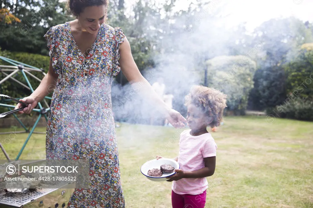 Mother and daughter barbecuing in summer backyard