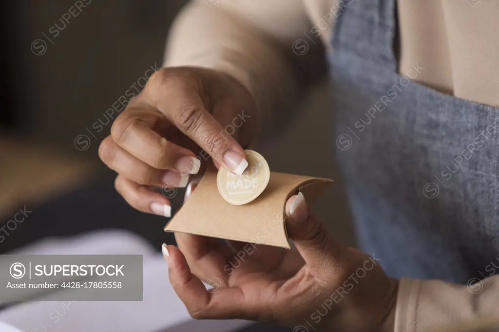 Close up female shop owner placing handmade label on box