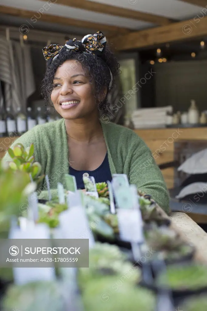 Happy female shop owner at succulent display in plant nursery