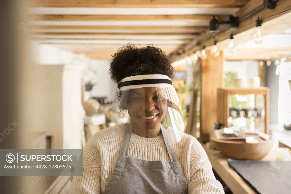 Portrait happy female shop owner wearing face shield