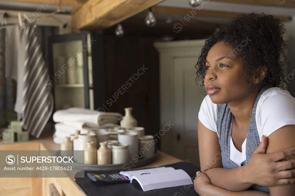 Thoughtful female shop owner at counter looking away in anticipation