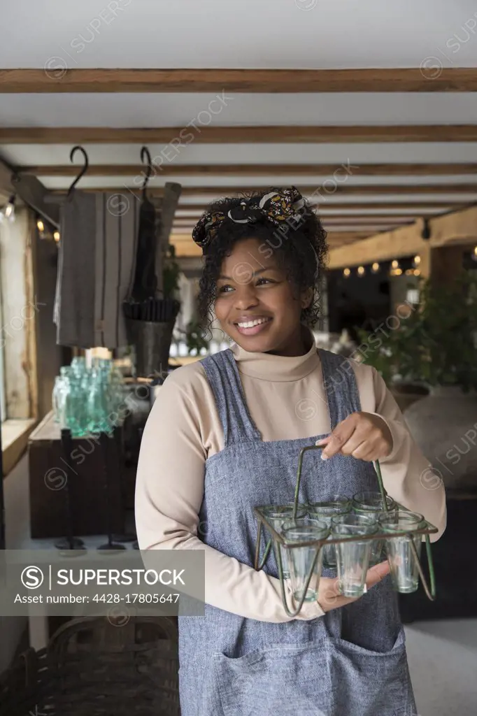 Portrait happy female shop owner holding glass plant holder