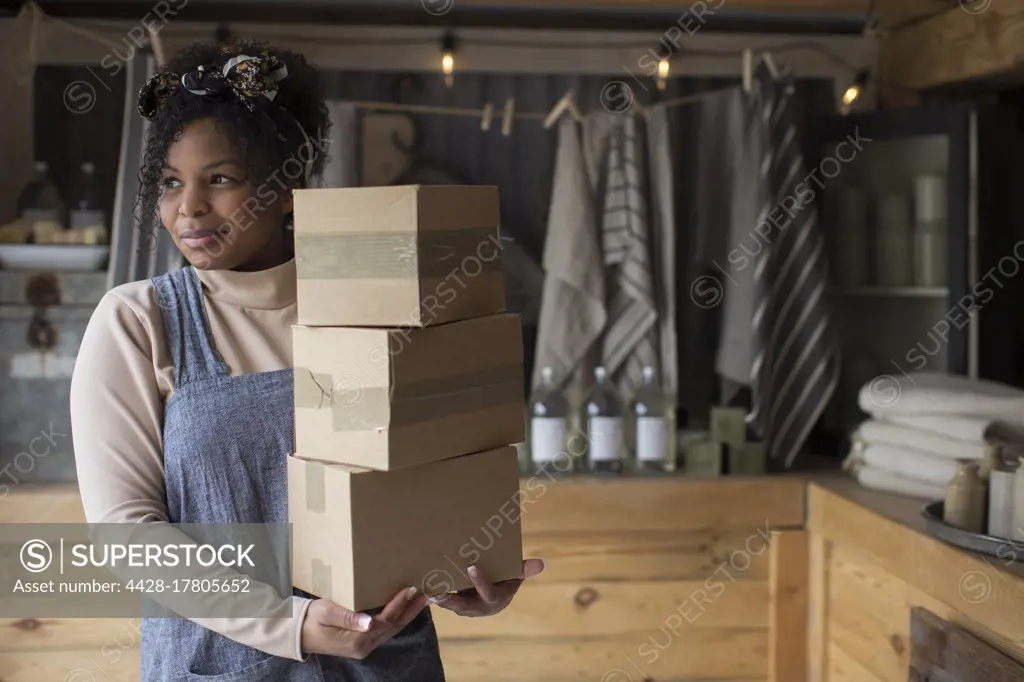 Portrait confident female shop owner with stack of cardboard boxes