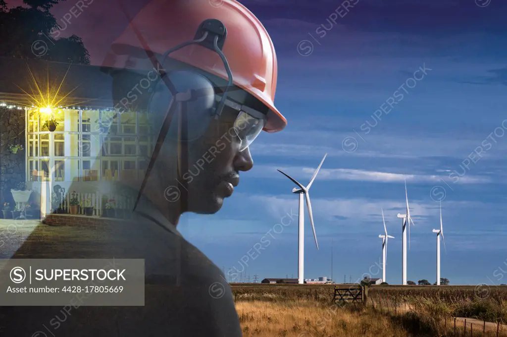 Male engineer in hard hat in field with wind turbines