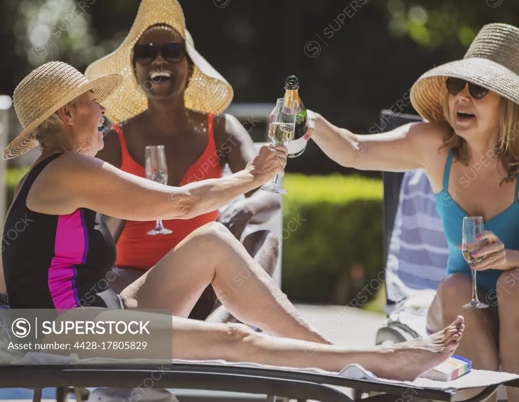 Happy senior women friends drinking champagne on sunny summer patio