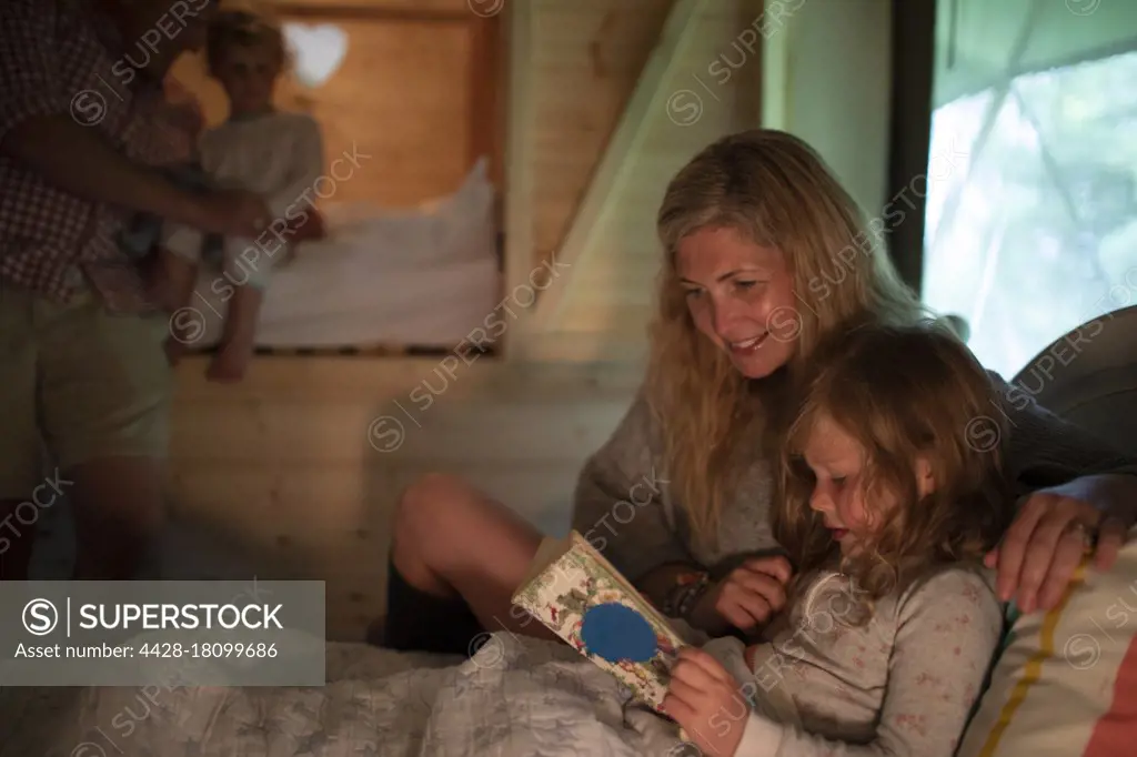 Mother and daughter reading bedtime story book in bed