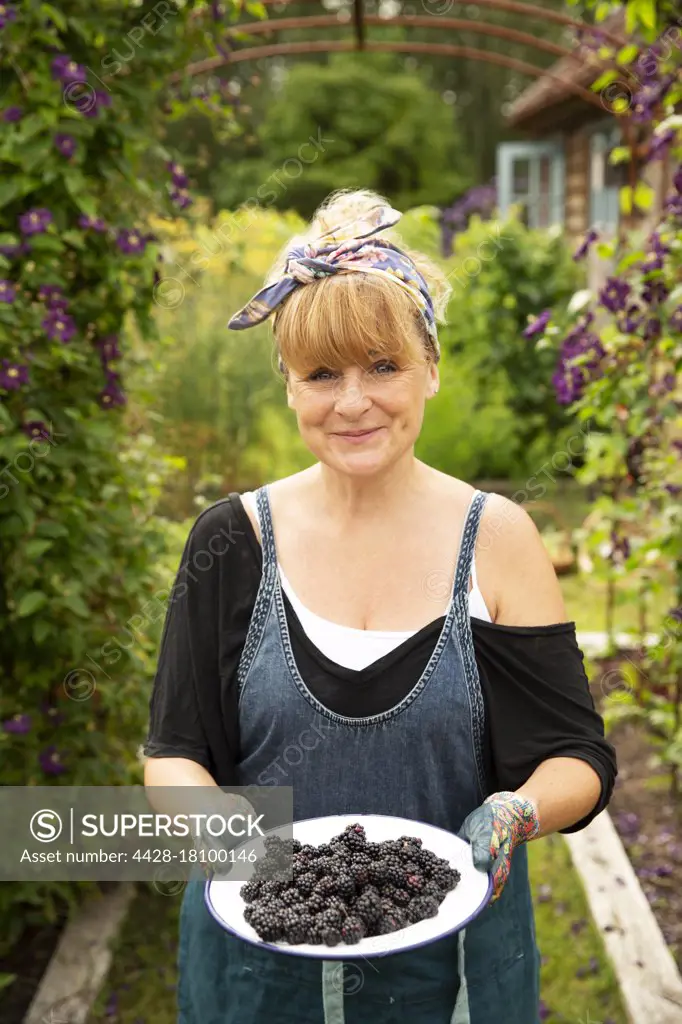 Portrait proud woman with fresh harvested blackberries in garden
