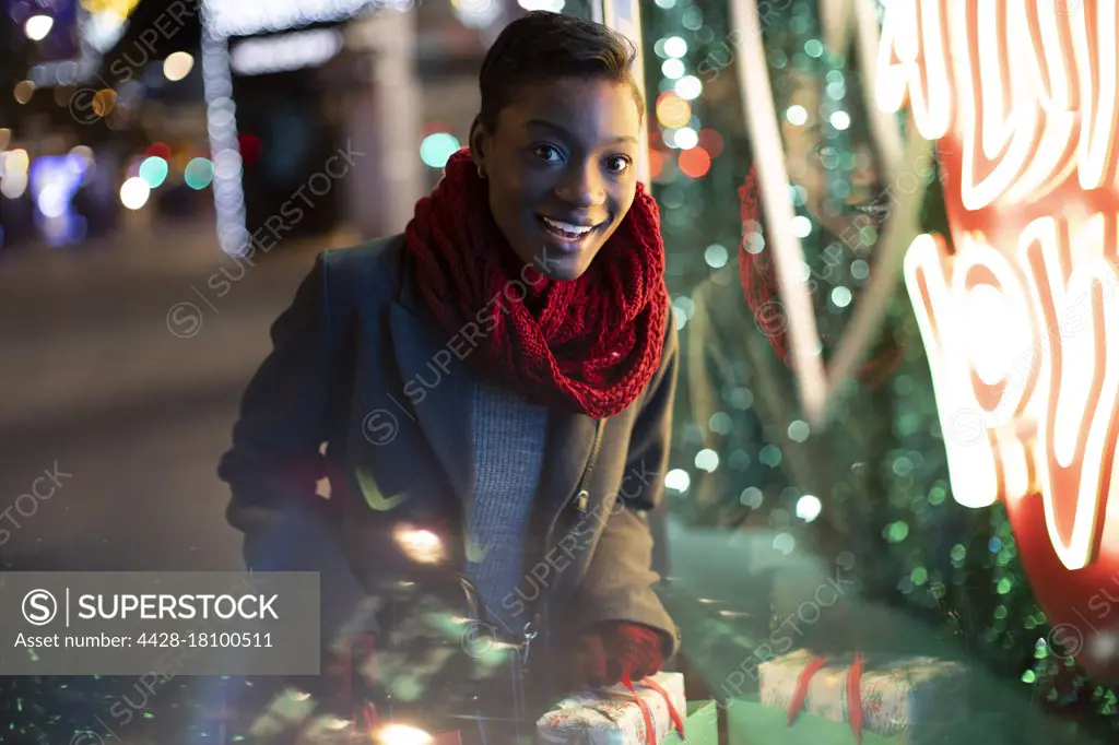 Portrait happy young woman Christmas shopping at neon storefront