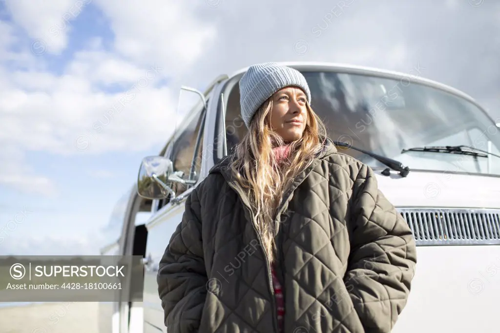 Portrait confident young woman in coat outside sunny van
