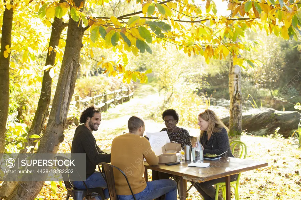 Creative business team meeting at table in sunny idyllic autumn park