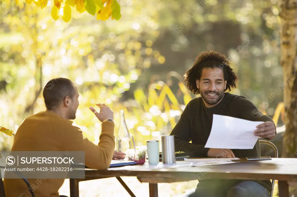 Businessmen discussing paperwork at table in autumn park