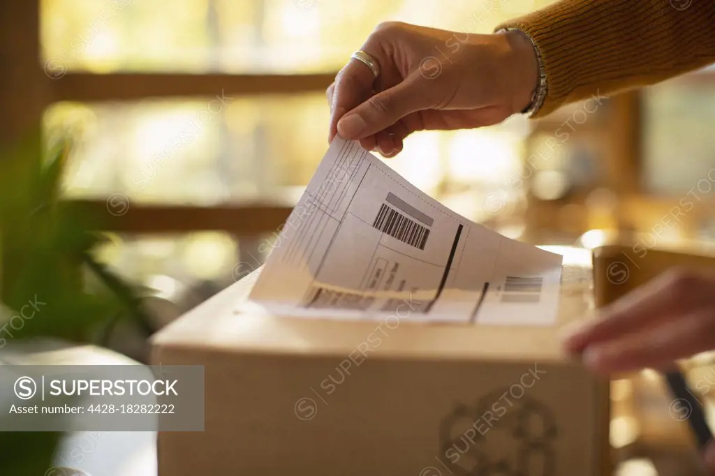 Close up business owner placing shipping label on package
