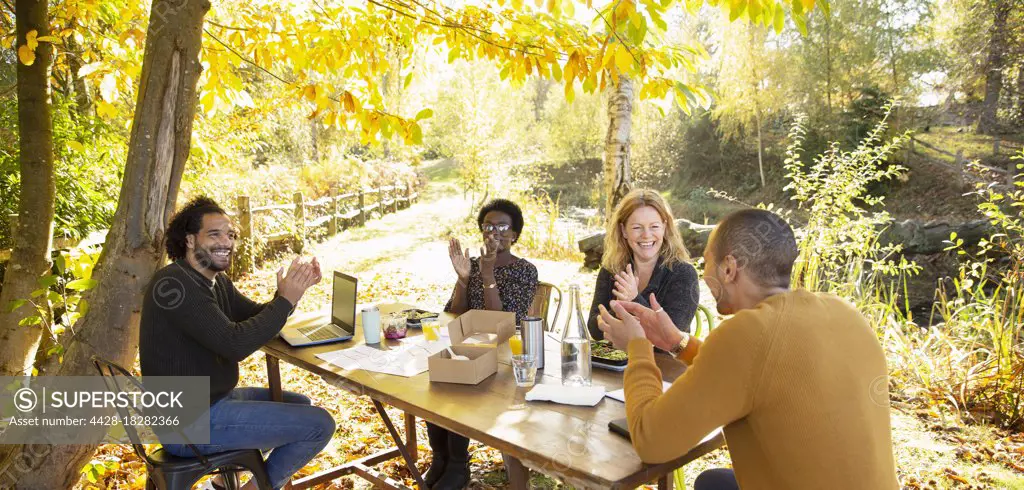Happy business people clapping and meeting in sunny autumn park