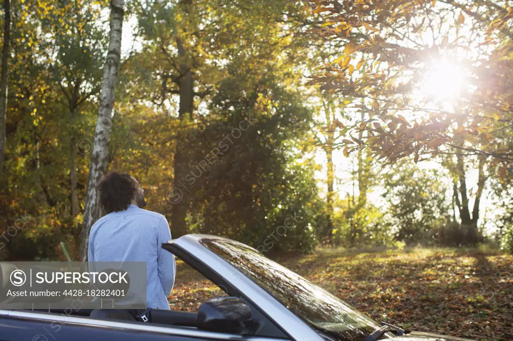 Man at convertible ins sunny autumn park