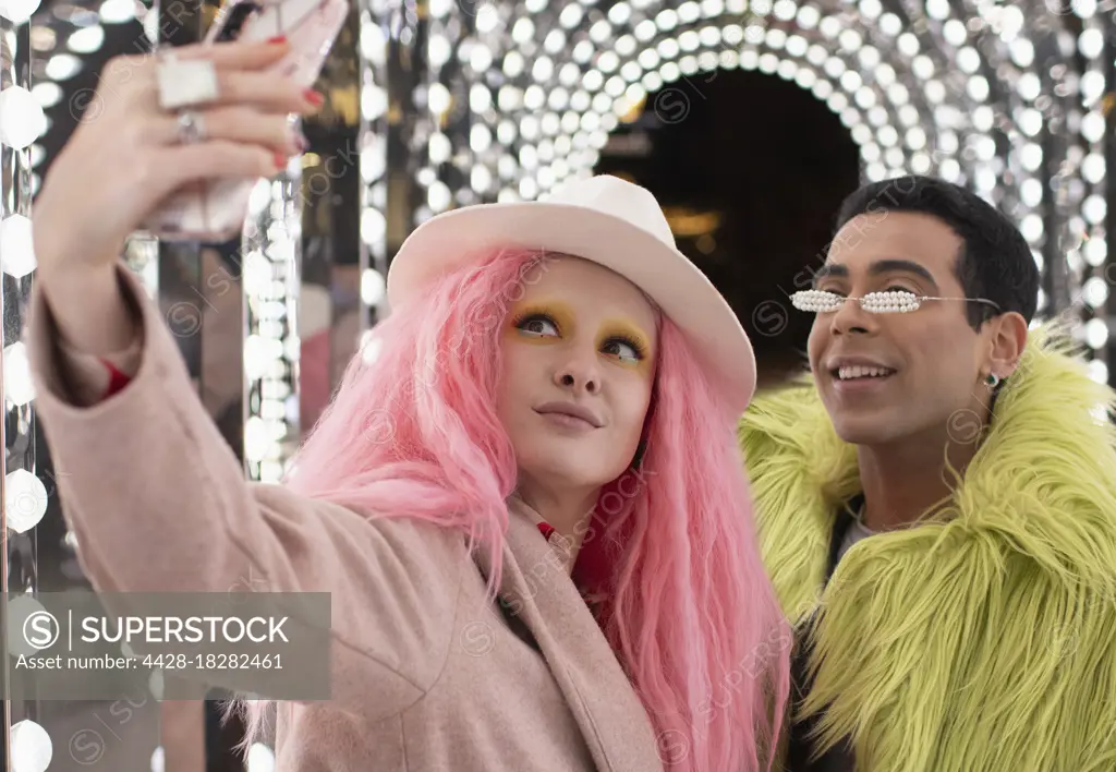 Eccentric fashionable couple taking selfie under arch lights
