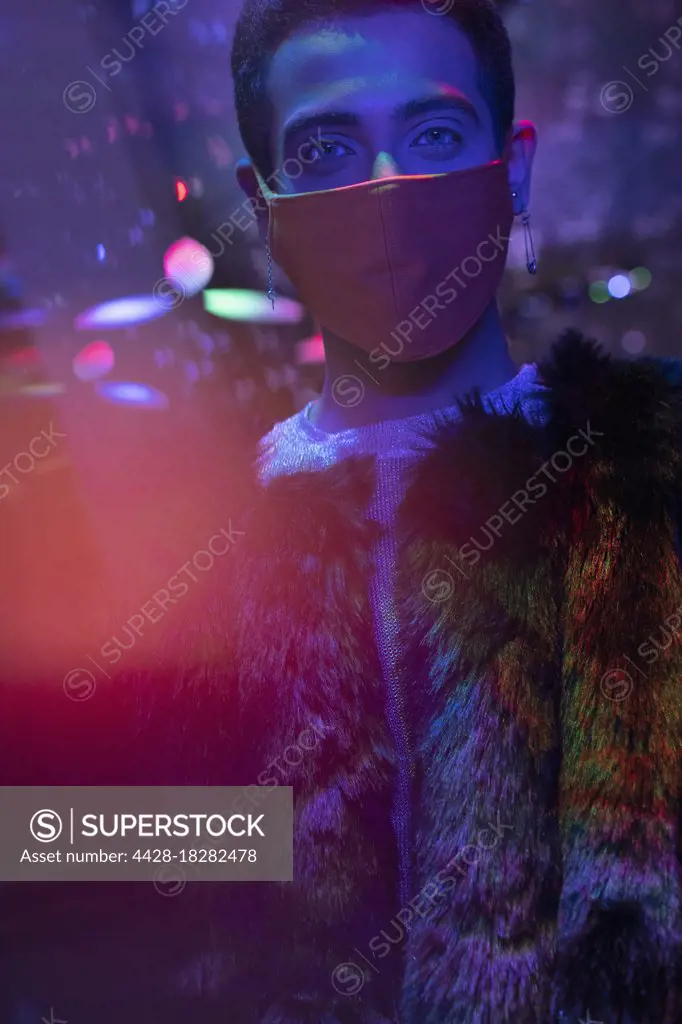 Portrait stylish young man wearing face mask in nightclub