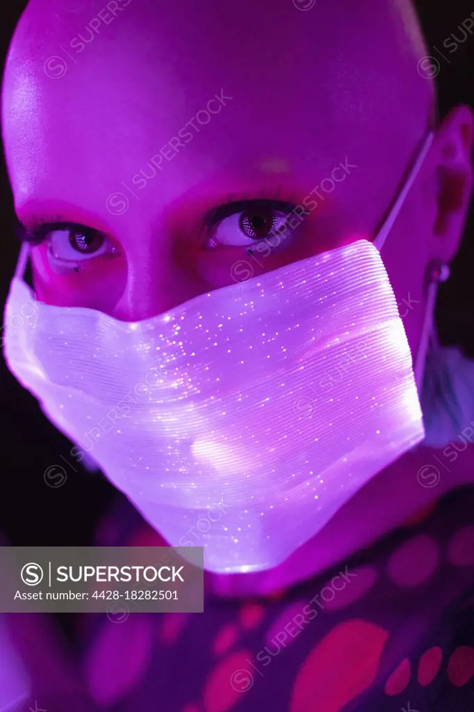 Close up portrait woman with shaved head in glowing face mask
