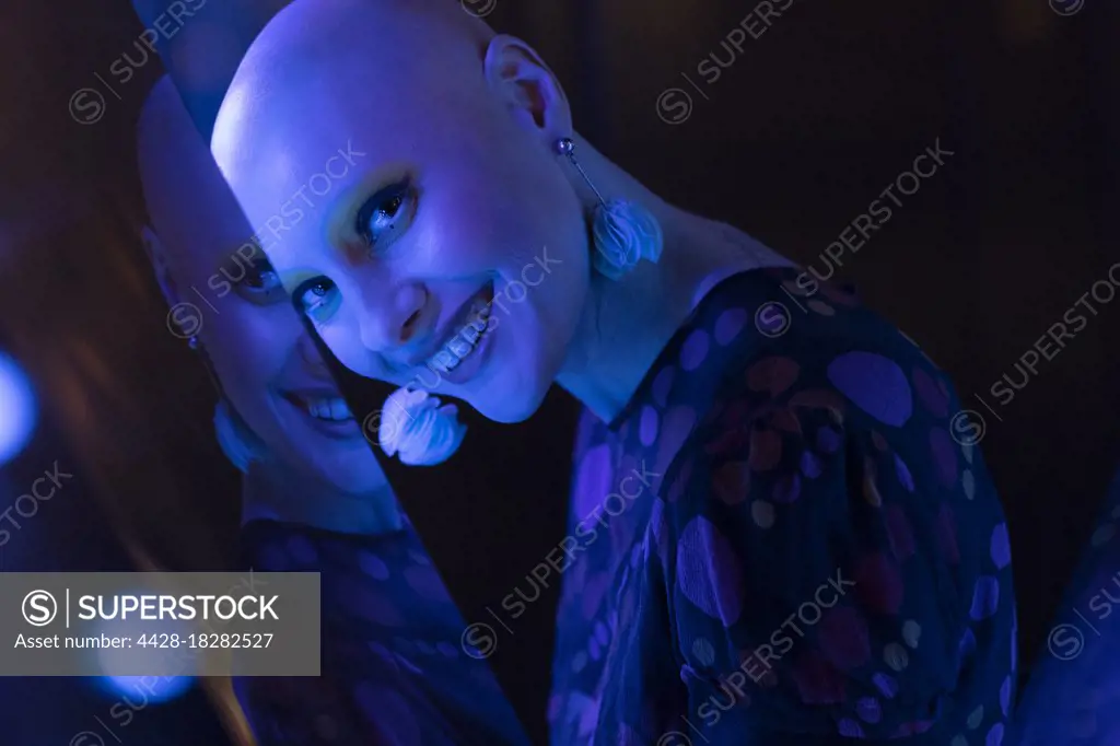 Portrait beautiful woman with shaved head in blue neon light