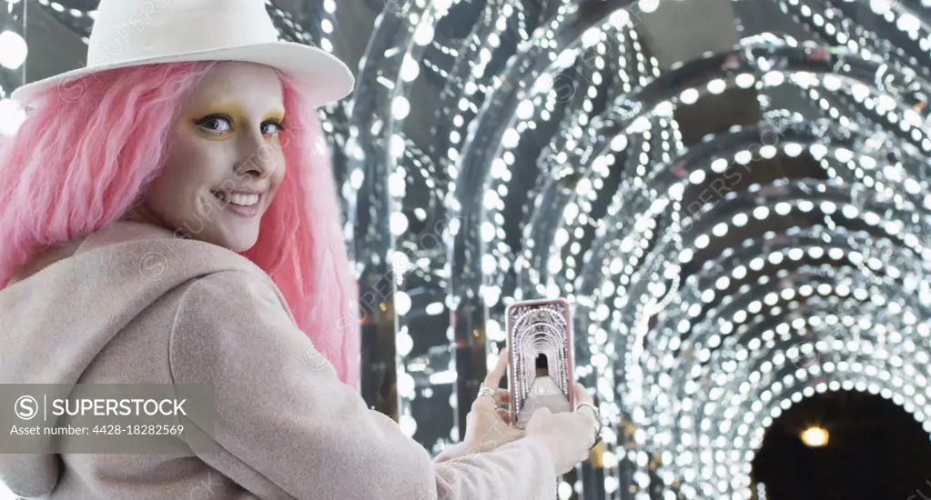 Portrait stylish woman with pink hair photographing arch lights