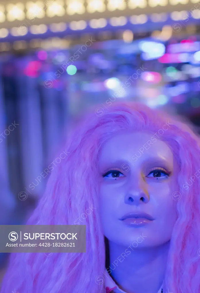 Portrait confident cool woman with pink hair under neon light