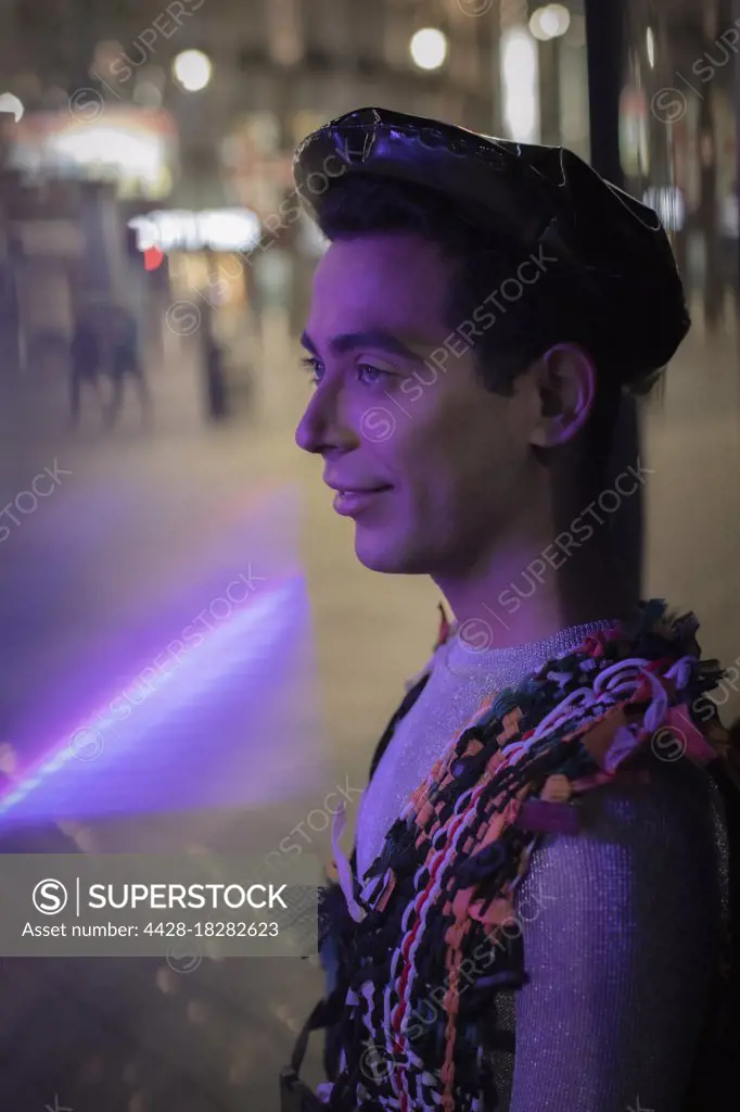 Eccentric young man on city sidewalk at night