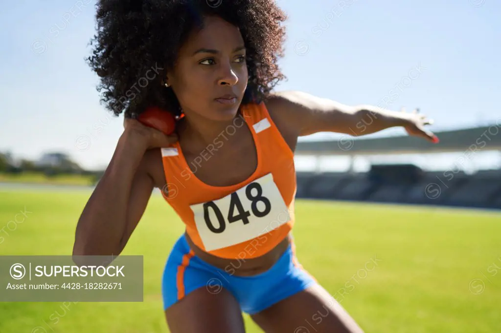Focused female track and field athlete throwing shot put