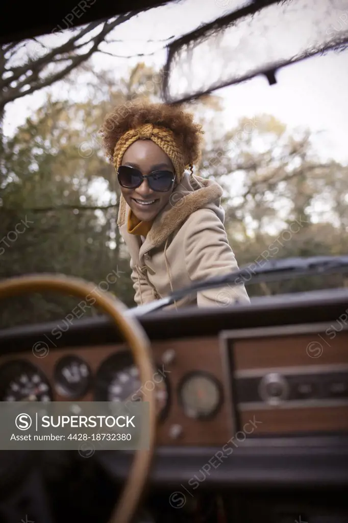 Portrait happy young woman outside convertible in park
