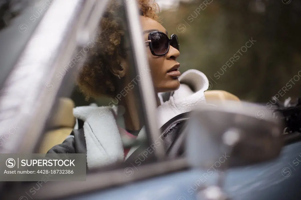 Young woman in sunglasses driving convertible