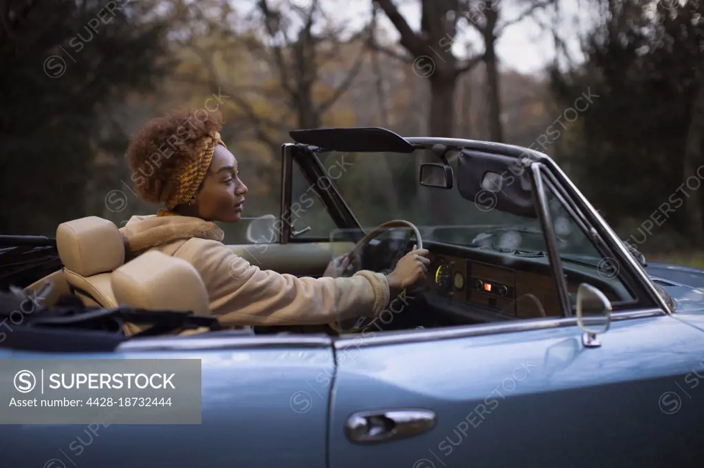 Young woman driving convertible in autumn park