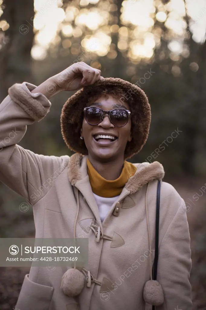 Portrait happy young woman in coat and hat in autumn park