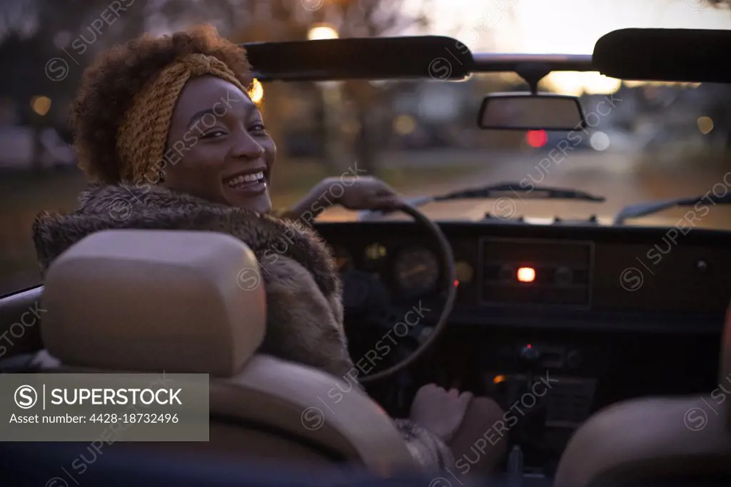 Portrait happy young woman driving convertible at night