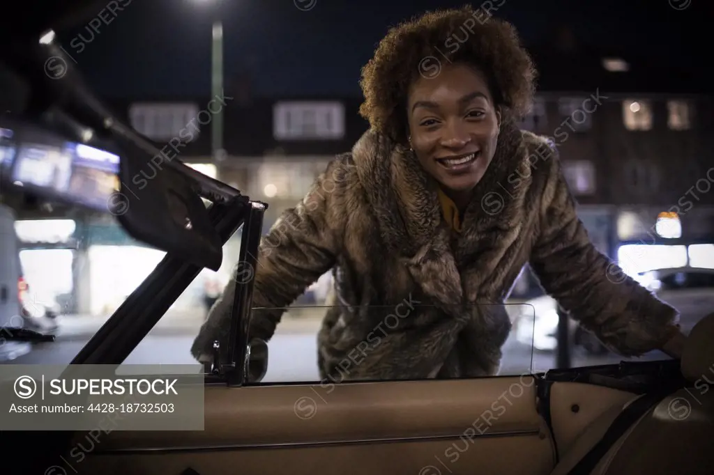 Portrait happy young woman outside convertible at night