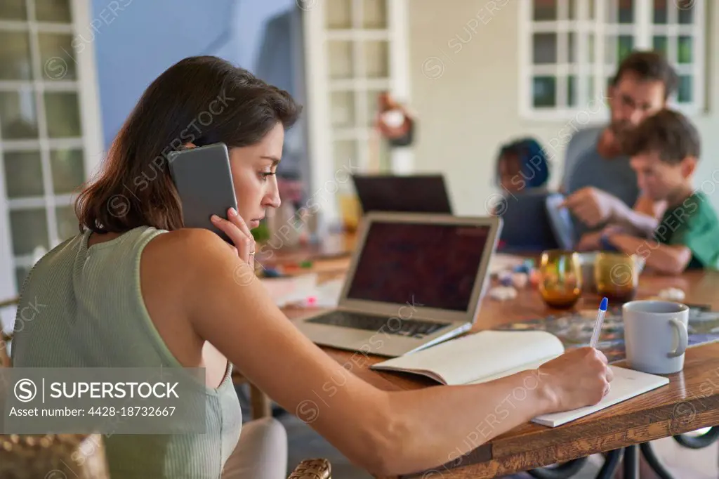 Woman working from home at dining table with family