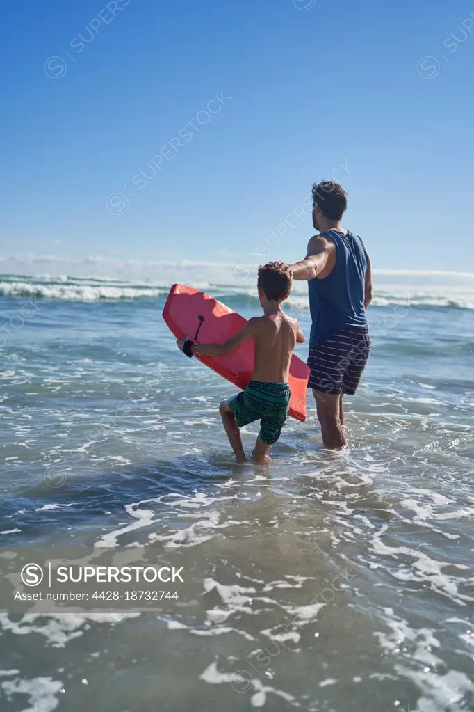 Father and son with body board in sunny summer ocean