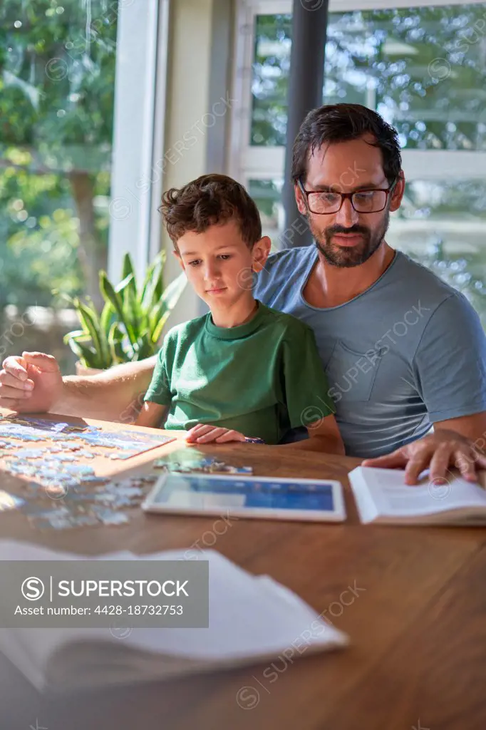Father and son reading and assembling jigsaw puzzle