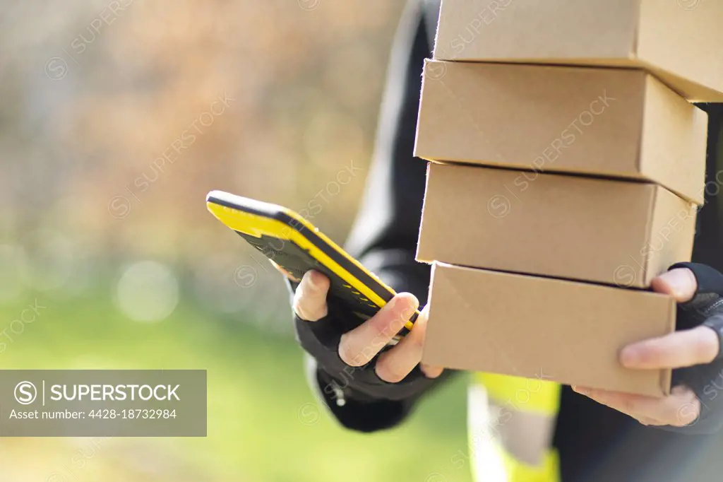 Close up courier with smart phone delivering packages