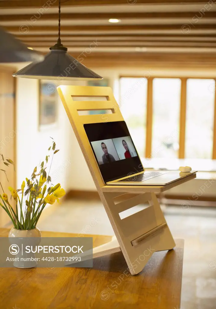 Business people video conferencing on laptop stand desk in kitchen