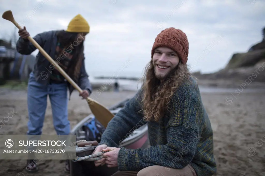 Portrait carefree young couple preparing canoe on beach