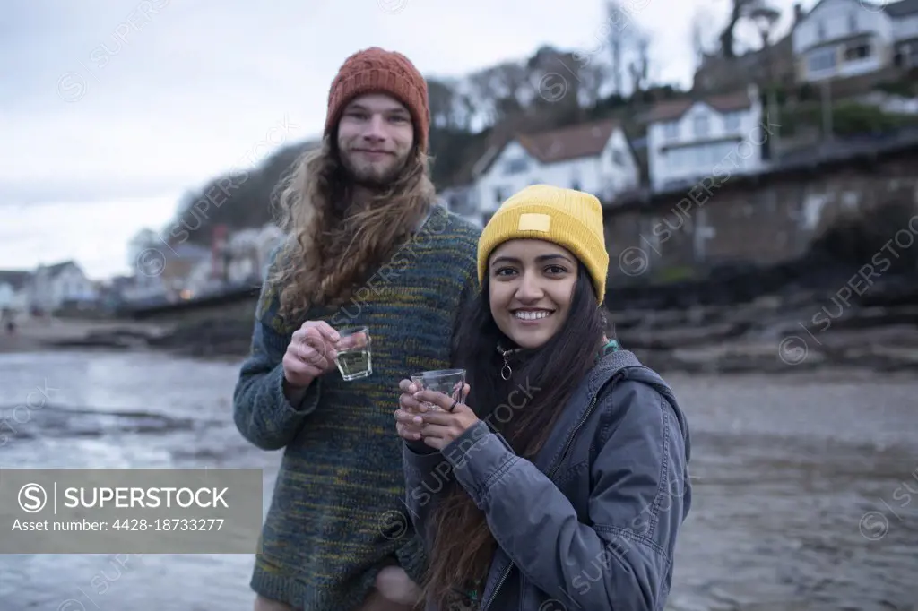 Portrait happy young couple drinking on cold beach