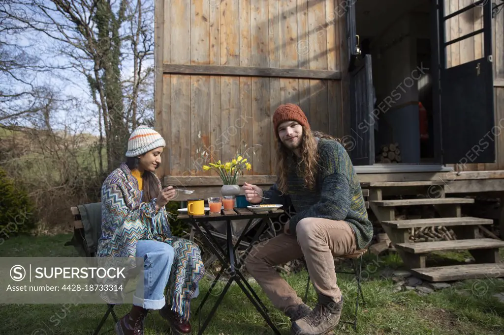 Portrait young couple eating at table outside tiny cabin rental