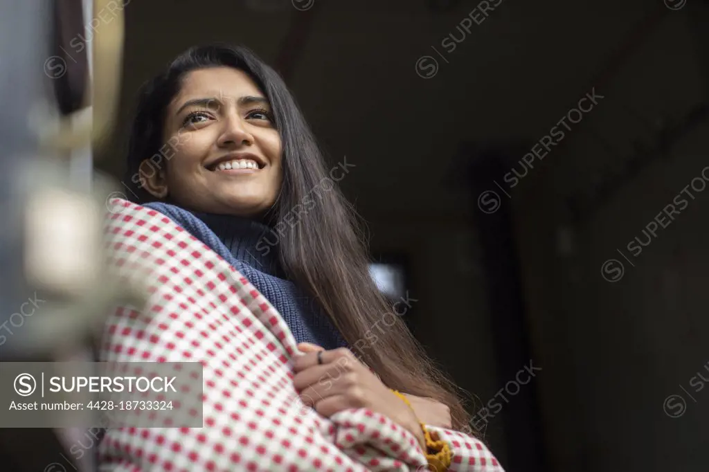 Happy young woman wrapped in a blanket