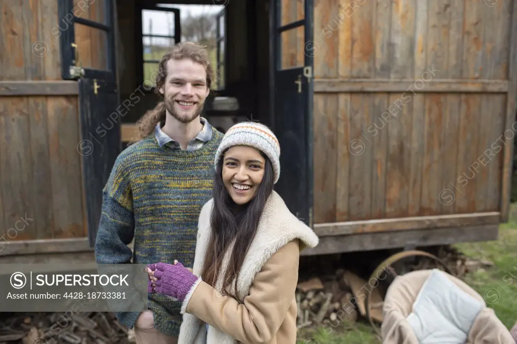 Portrait happy young couple outside tiny cabin rental