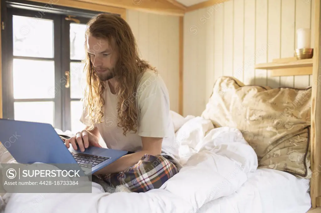 Young man using laptop in bed