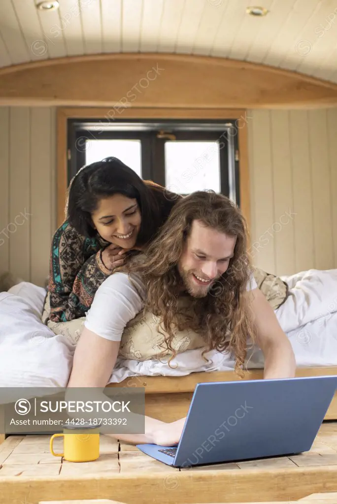 Happy young couple using laptop in tiny cabin